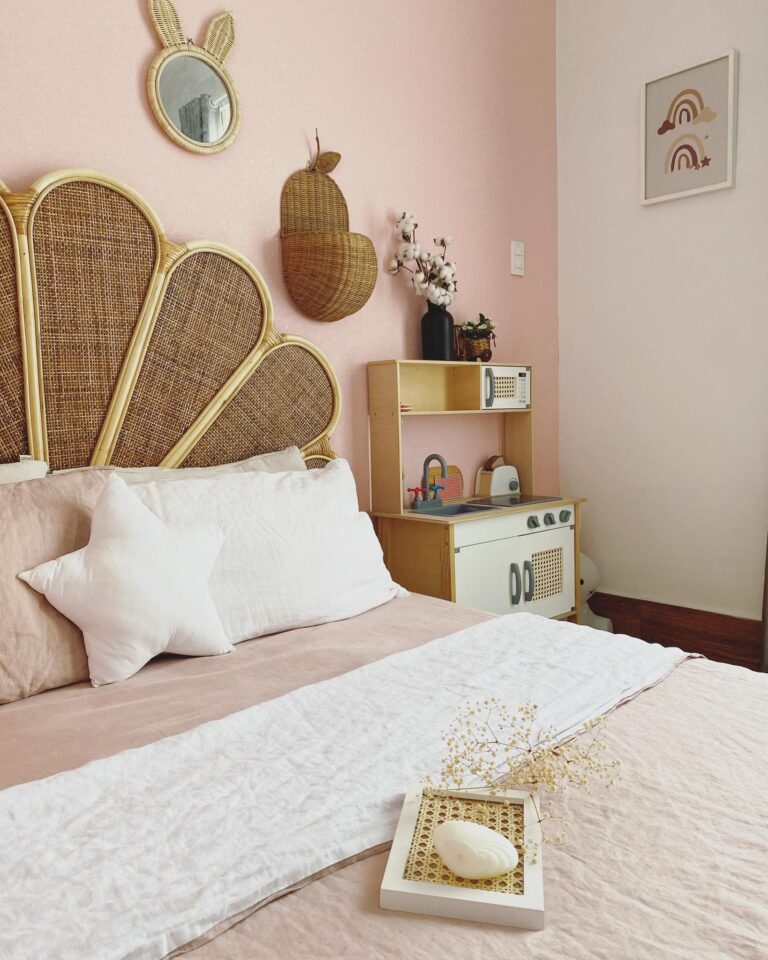 Phòng ngủ boho nhẹ với chăn ga gối linen trắng, mây tre và tường hồng phấn