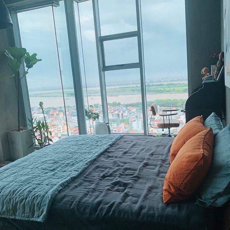 Phòng ngủ căn hộ với chăn ga gối linen xanh đá phiến và tầm nhìn thành phố